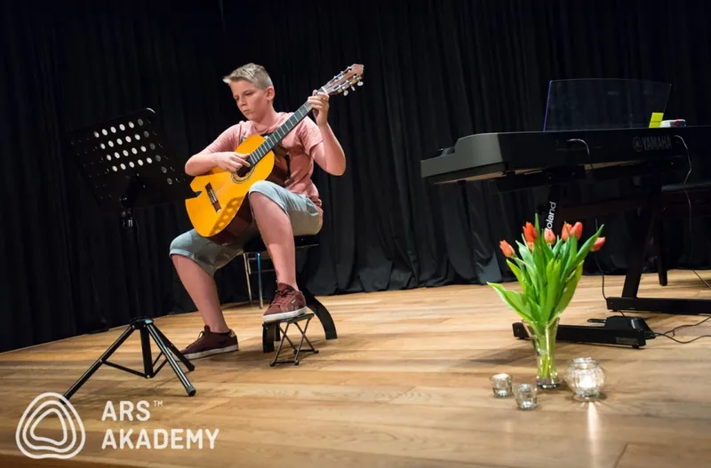 Žiak hrá na gitare na hudobnej besiedke